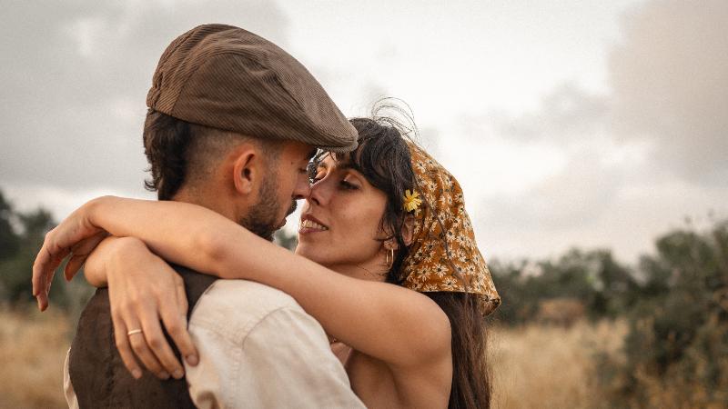 זוג מחובק, אף אל אף, מול שמיים מעוננים — צילומי זוגיות