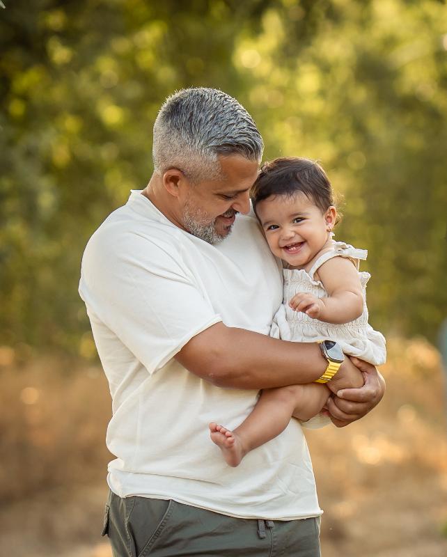 אבא מחבק פעוטה צוחקת באור זהוב — צילומי גיל שנה ומשפחה